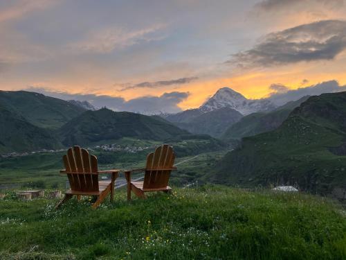 two chairs sitting on a hill with a view of mountains at Kazbegi Hills Cottages in Stepantsminda