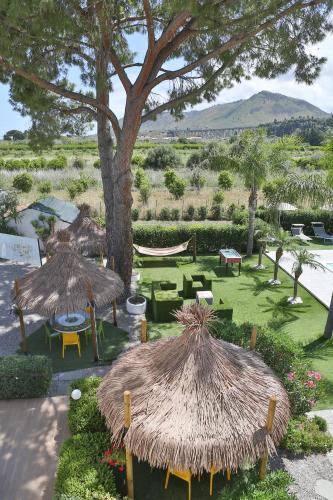 two straw umbrellas and a hammock in a garden at Le Zagare in Lascari