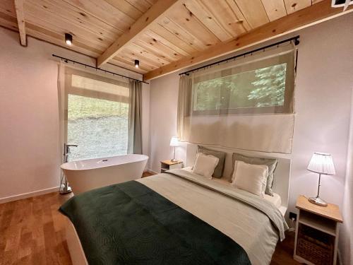 a bedroom with a bed and a bath tub and a window at Rogaty Domek przy Bobrowisku in Kornatka