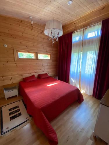 a bedroom with a red bed in a wooden room at Mukava mökki kompleksi Saimaan rannalla in Mikkeli