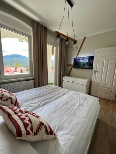 a bedroom with a large white bed with a window at Apartament Villa Nelly in Szklarska Poręba