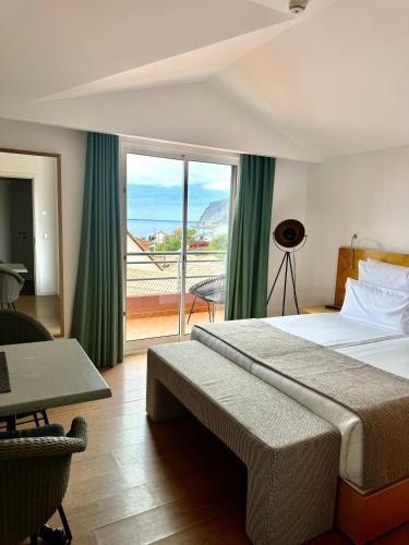 a hotel room with a bed and a large window at Boutique Hotel Jardim Do Mar in Jardim do Mar