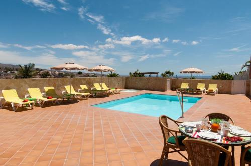 a patio with a table and chairs and a pool at Villa Los Azules with pool and jacuzzi in Maspalomas
