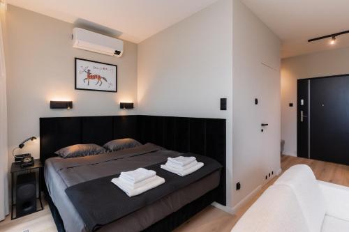 a bedroom with a black bed with towels on it at Riverside City View & free parking in Rzeszów