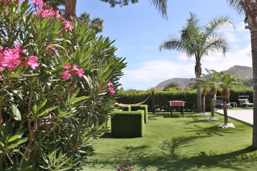 a garden with pink flowers and palm trees at Le Zagare in Lascari