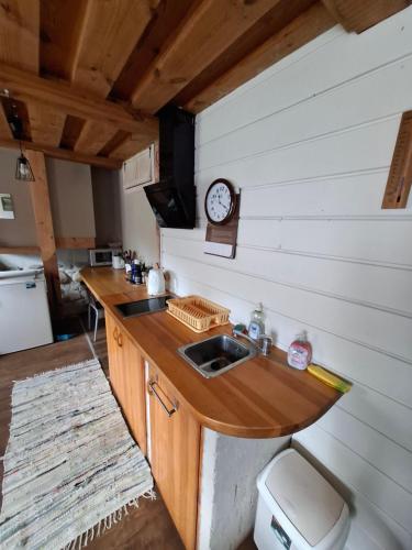 a kitchen with a sink and a clock on the wall at Viļņi in Ulmale