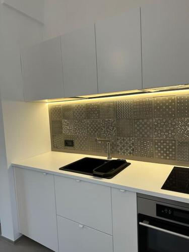 a kitchen with white cabinets and a sink at Design, comfort e atmosfera nel cuore del Salento in Martano