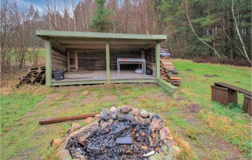 a building with a fire pit in a field at Lovely Home In Skånes Fagerhult in Skånes Fagerhult