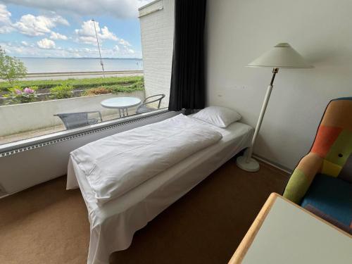 a bedroom with a bed and a chair and a window at Hotel Østersø in Aabenraa