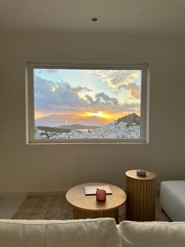 a living room with a window with a view of a city at Skala Sunset Hotel and spa in Ios Chora