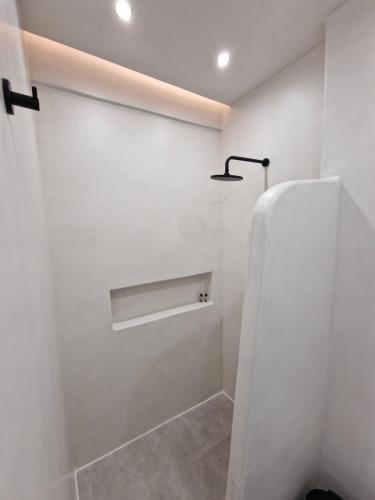 a bathroom with a white wall and a light at Smaro Studios in Firostefani
