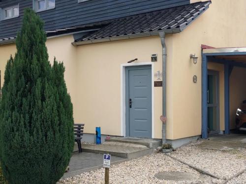 a house with a blue door and a pine tree at Ferienwohnung am See in Pomssen