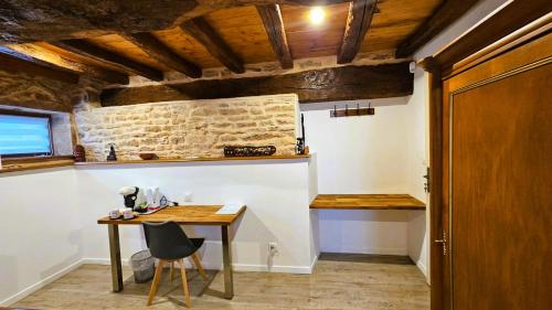 a table and chair in a room with a stone wall at La GRANGE D'AZE in Azé