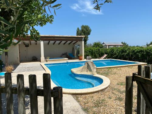 - une piscine dans une cour avec une clôture en bois dans l'établissement Les Pierrades en Camargue, à Vauvert