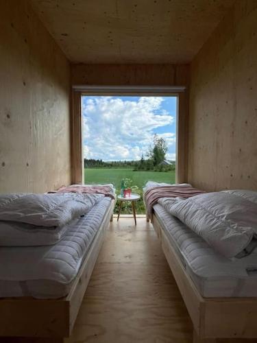 two beds in a room with a large window at KoloCabins - Hiitolanjoki 1 in Simpele