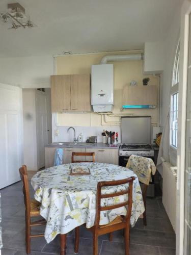 une cuisine avec une table et des chaises ainsi qu'une cuisine avec une cuisinière dans l'établissement LouiseHélène, à Merville-Franceville-Plage