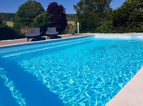 - une piscine bleue avec 2 chaises dans l'établissement Villa Campagne Chic, à Meulers