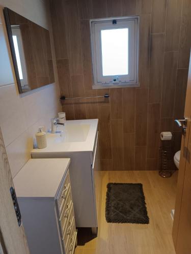 a bathroom with a white sink and a window at Moradia Largo do Pátio in Sertã