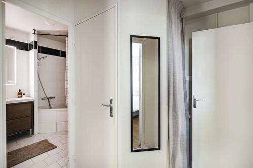 La salle de bains blanche est pourvue d'une douche et d'un miroir. dans l'établissement Playground Suite, à Créteil
