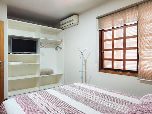 a bedroom with a bed with a television and a window at Saint Moritz 204 a 2 quadras da Rua Coberta in Gramado