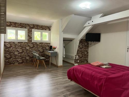 une chambre avec un lit et un mur en pierre dans l'établissement La Maison de Tina, à Lanzac