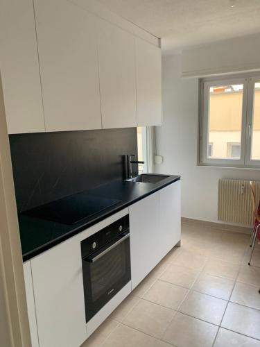 a kitchen with white cabinets and a black counter top at Appartement en face de la gare de St-Louis in Saint-Louis
