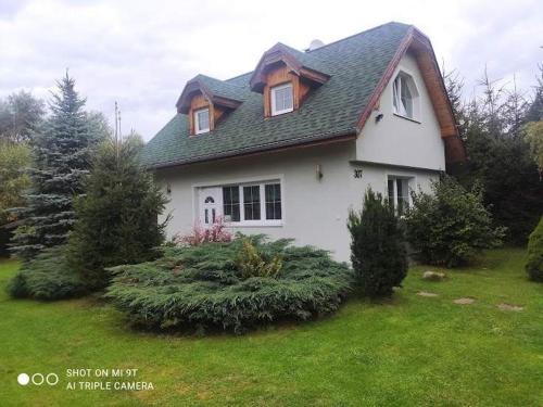 a white house with trees and bushes in a yard at apartman domček in Liptovský Trnovec