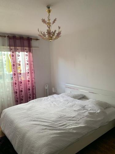 a bedroom with a white bed and a chandelier at Appartement en face de la gare de St-Louis in Saint-Louis