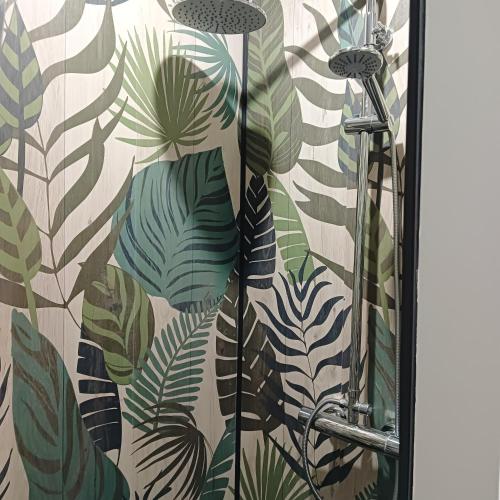 eine Dusche mit einem Wandgemälde tropischer Blätter in der Unterkunft Gîte de la Duranderie in Sevremont