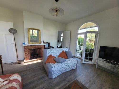 ein Wohnzimmer mit Sofa und Kamin in der Unterkunft LouiseHélène in Merville-Franceville-Plage