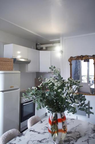 une cuisine avec un vase de fleurs sur une table dans l'établissement Charmant deux pièces au coeur du Marais, à Paris