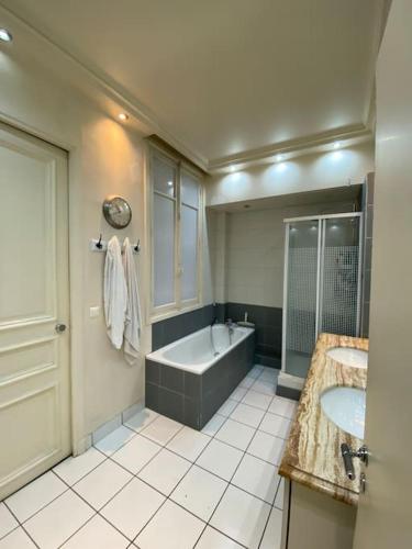 La salle de bains est pourvue d'une baignoire, de 2 lavabos et d'une baignoire. dans l'établissement Paris - Appartement - 16eme, à Paris