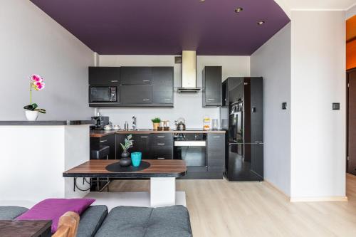 a kitchen and living room with black cabinets and a table at SuperApart Pożarowa 3B, parking in Warsaw