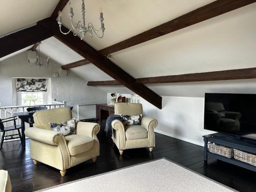 a living room with two chairs and a tv at Penthouse apartment in Cockermouth