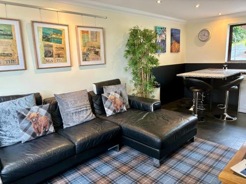 a leather couch in a living room with a piano at Misty Isle Apartments Ltd - Maol View in Kyleakin