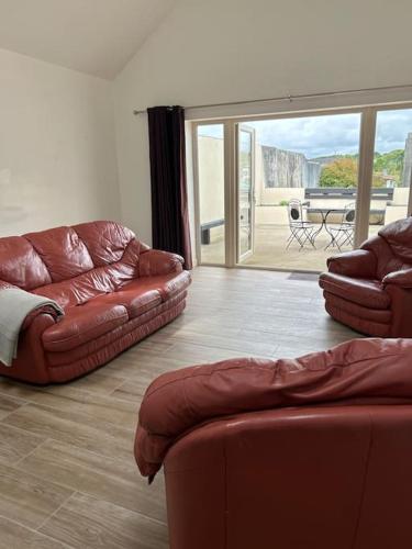 a living room with two leather couches and a patio at The Parlour Cottage in Galway