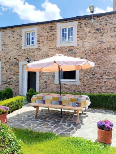 a bench with an umbrella in front of a building at Casa Lolita 1 in Viveiro