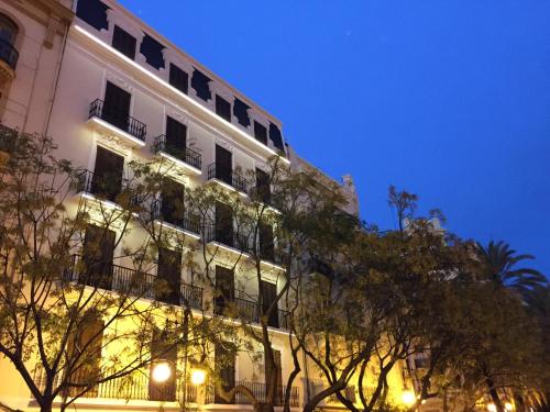 a tall white building with windows and trees at night at Soho Valencia in Valencia