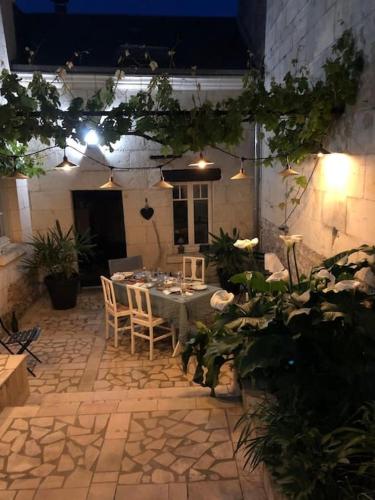 d'une terrasse avec une table, des plantes et des lumières. dans l'établissement Ancien pressoir, semi-troglodyte, à Turquant