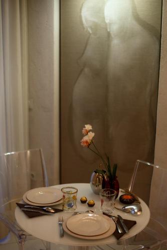 a table with plates and a vase with flowers on it at Art Boutique Hotel Acchiappasogni in Barga