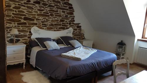 une chambre avec un lit avec un mur en pierre dans l'établissement Manoir de Kerguezec 15e S -Bretagne-Morbihan-SURZUR, à Surzur