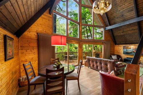 a dining room with a table and chairs and windows at Honey Bear - Unique Boutique Chalet in Gatlinburg with Mt Leconte view in Gatlinburg