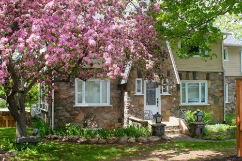 a house with a pink flowering tree in front of it at Rester Vivant Chambres d'hôtes in Saint-Jean-Port-Joli