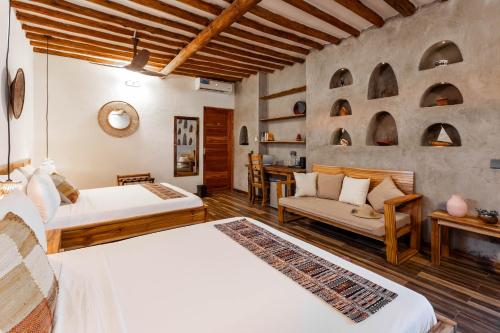 a bedroom with two beds and a couch and a table at Casa Ananda Boutique Hotel in Paje