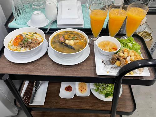 une table avec des bols de nourriture et des verres de jus d'orange dans l'établissement Louis Mo Apartment, à Đà Nẵng