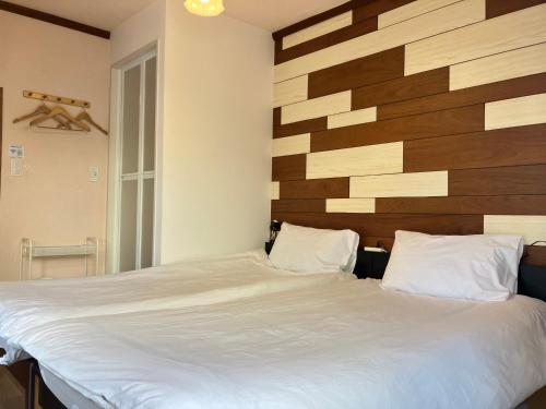a bedroom with a bed with a wooden headboard at Waraku No2,Guesthouse near KIX in Izumi-Sano