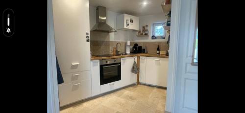 une cuisine avec des armoires blanches et un four à plaques de cuisson dans l'établissement Appart 2 min de la plage, à Benerville-sur-Mer