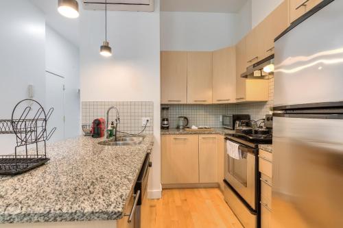 a kitchen with white cabinets and granite counter tops at Take a break in a modern loft on Plateau-Mont-Royal in Montréal