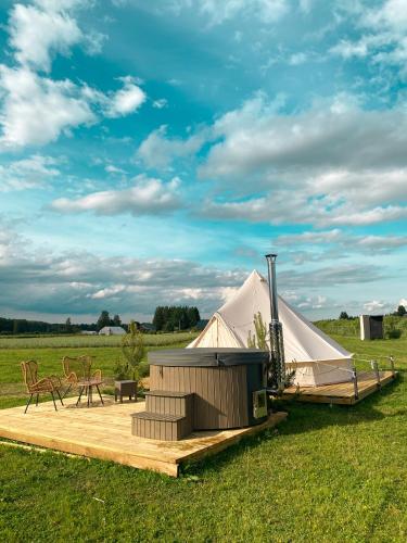 a large white tent in a field with chairs at Glempings MIGLA in Dalbe