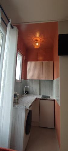 - une cuisine avec des murs rouges et un comptoir blanc dans l'établissement Studio La CASITA COZY- la Défense - Paris St lazare, à Colombes